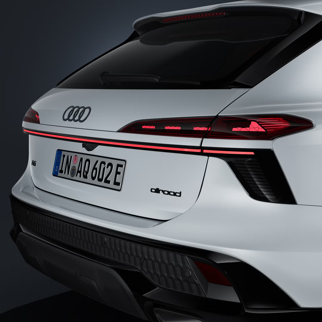 Šikmý detailný záber na zadnú časť vozidla s koncovými svetlami a svetelným pásom modelu Audi A6 allroad e-hybrid.