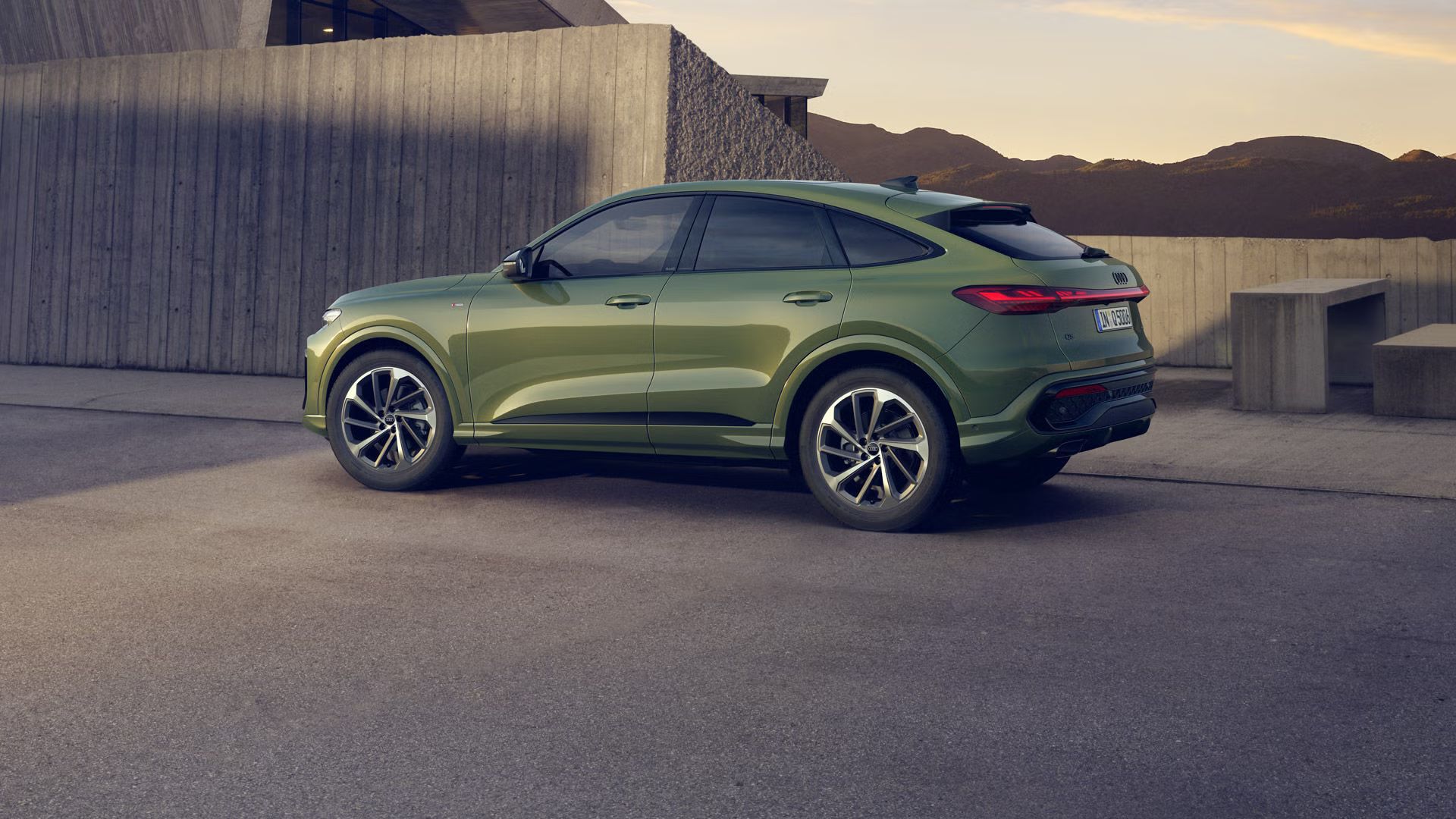 Zelené Audi Q5 Sportback z bočného pohľadu stojí na parkovisku pred vilou v horskom prostredí.