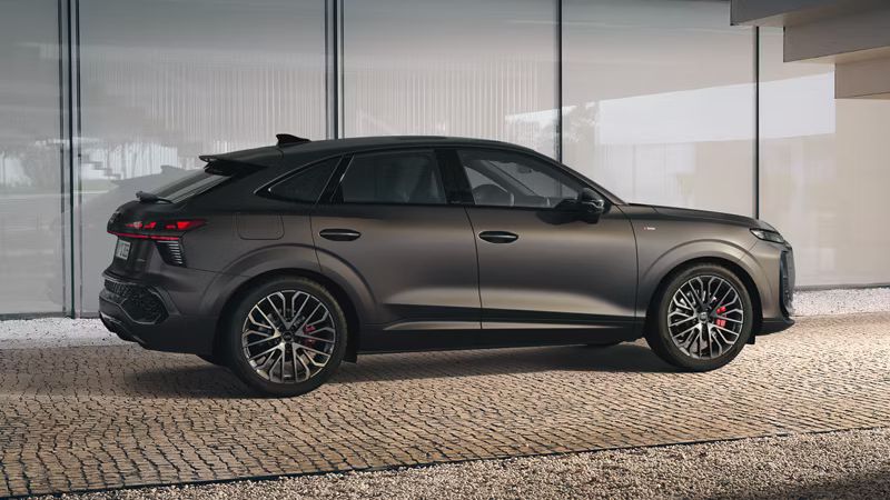 Audi Q3 Sportback stojí pod schodmi pri modernej budove. Pohľad zboku ponúka detailnejší náhľad na detaily exteriéru.en Details der Außenseite.