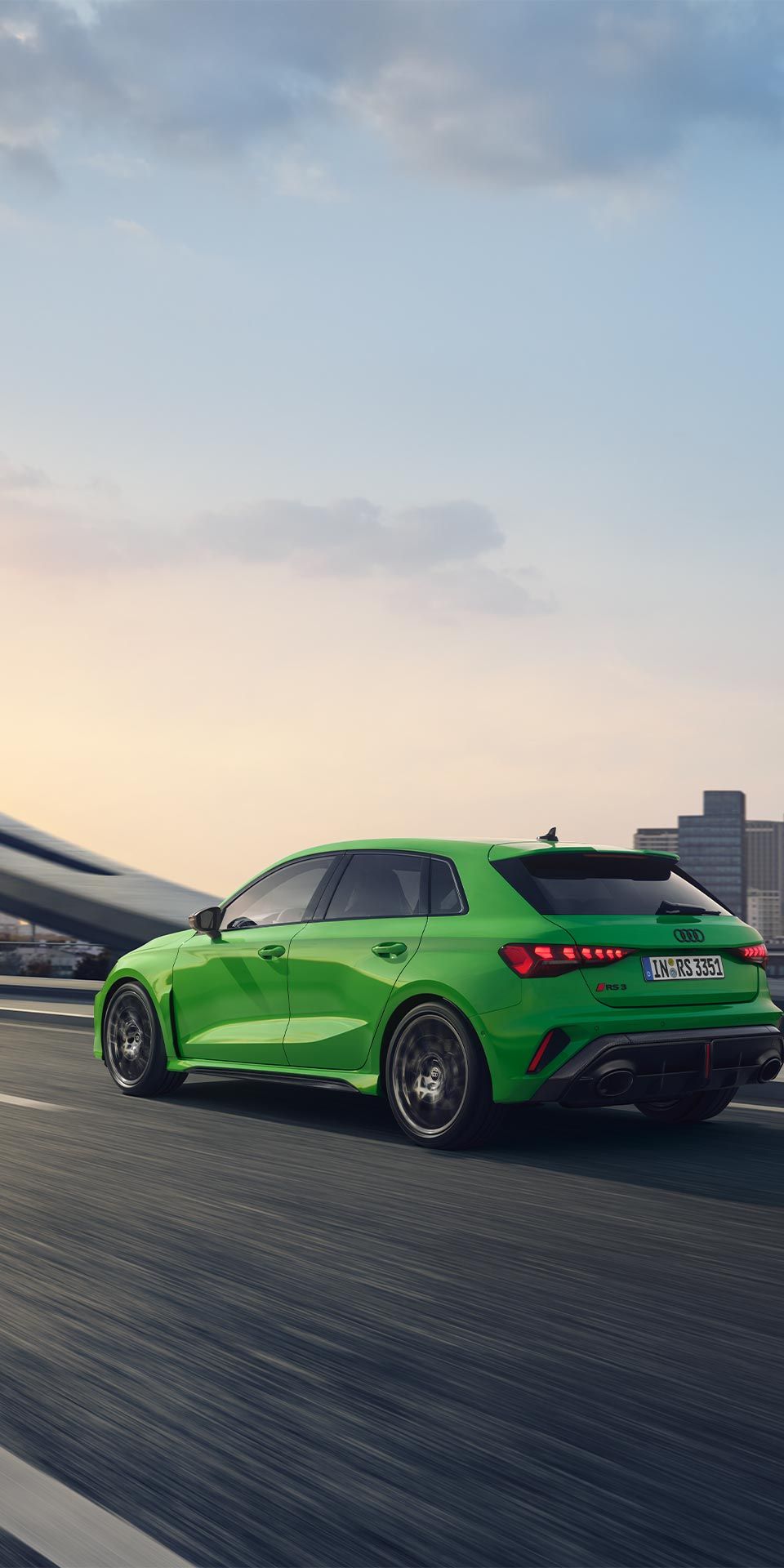 Seitliche Heckansicht eines grünen Audi RS 3 Sportback, der eine Straße entlangfährt