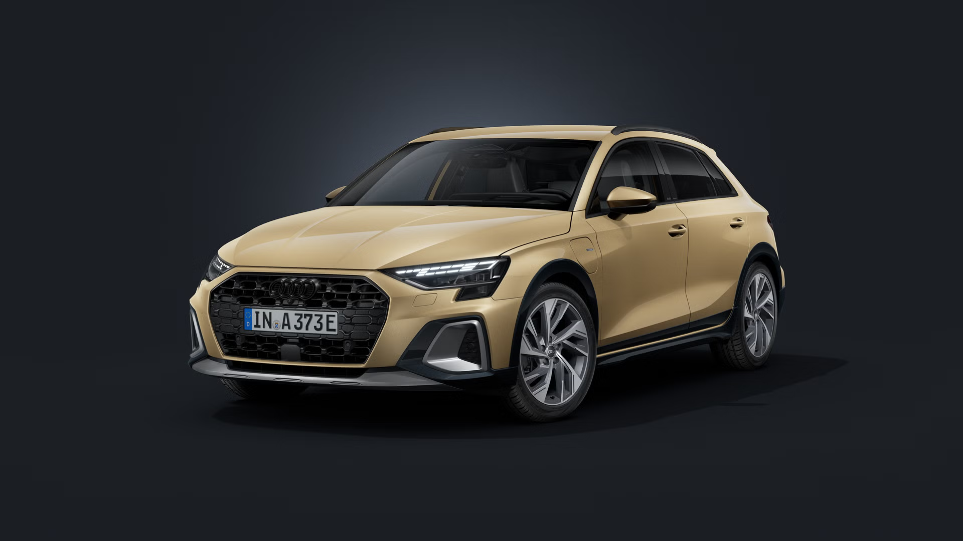 Audi A3 allstreet e-hybrid s individuálnym lakovaním Audi exclusive v odtieni Sandbeige s perleťovým efektom, zobrazené z čelného pohľadu šikmo na tmavom pozadí.