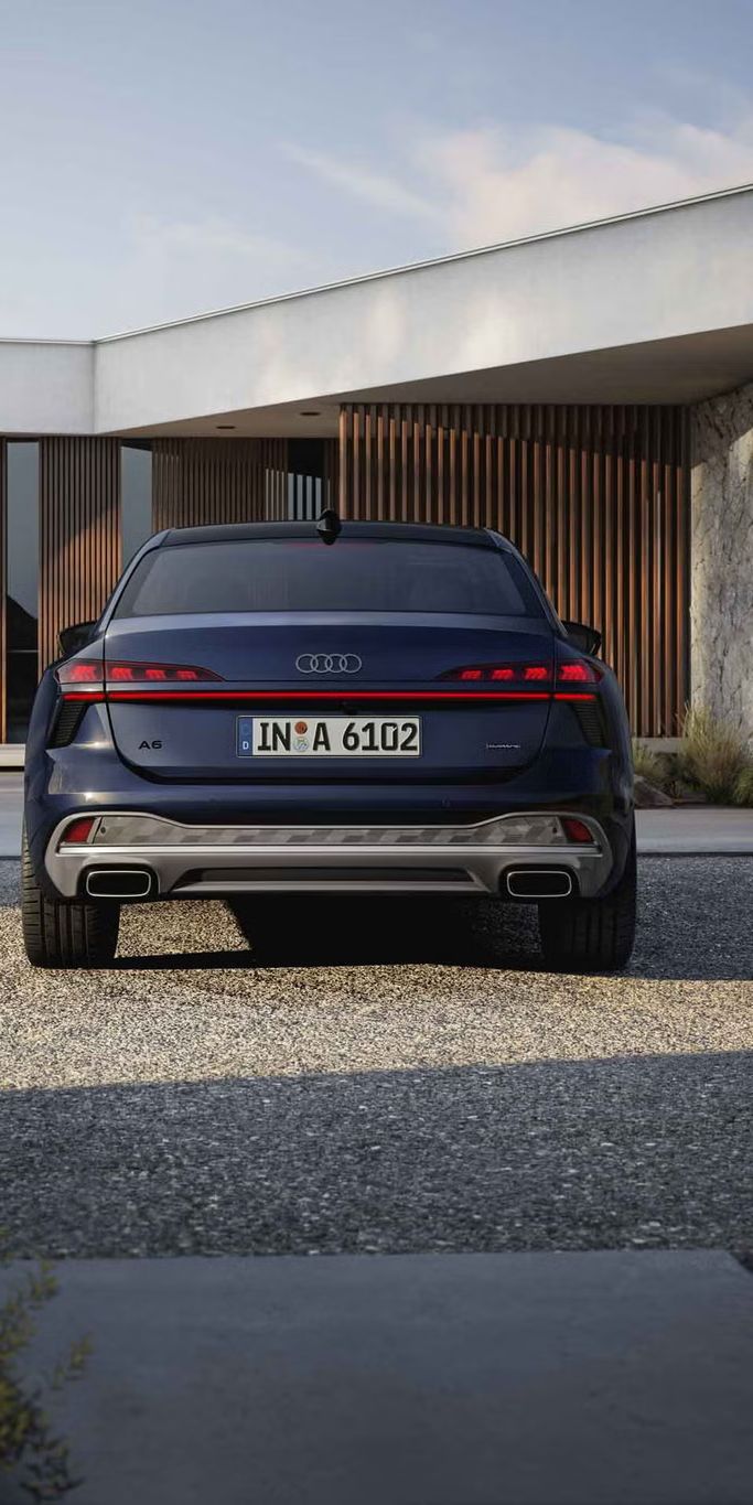 Die A6 Limousine in der Heckperspektive. Das Fahrzeug steht einem modernen Haus zugewandt.