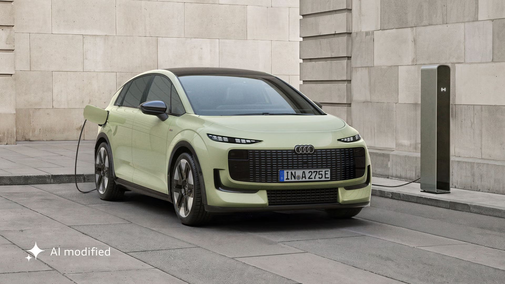 Audi A2 e-tron je zaparkované pred modernou budovou. Vozidlo je pripojené k nabíjacej stanici.