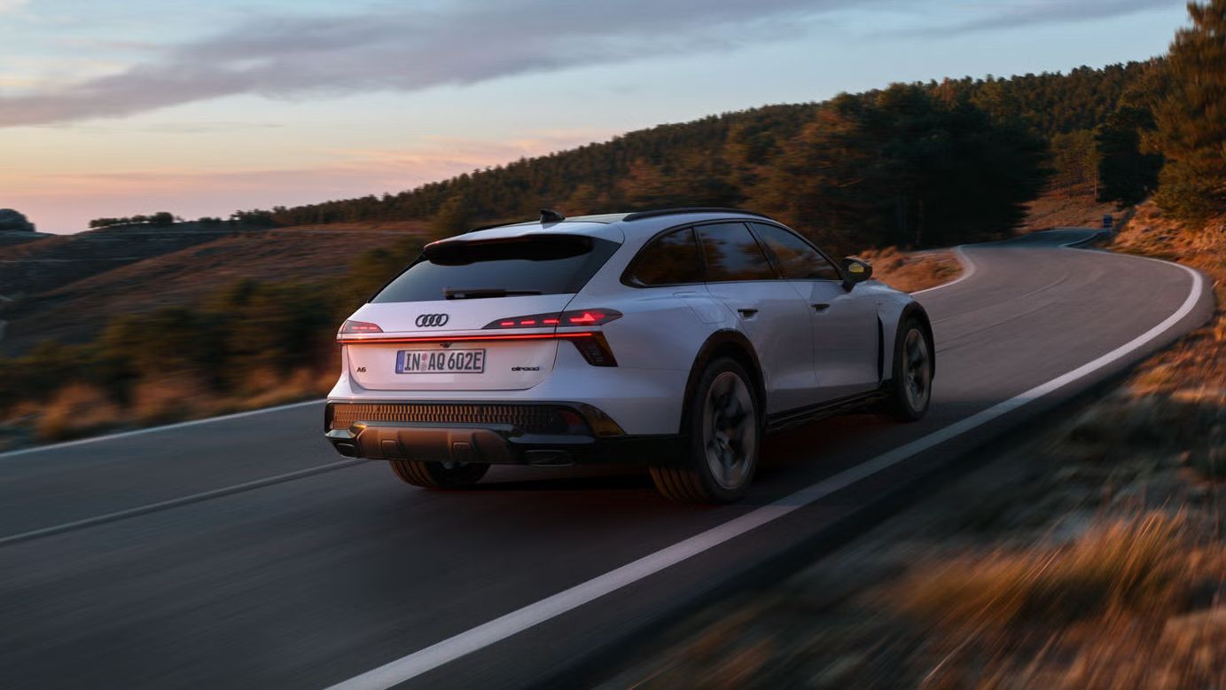 Audi A6 allroad e-hybrid zachytené z bočného pohľadu zo zadnej strany pri plnej rýchlosti na horskej ceste. V pozadí je les.
