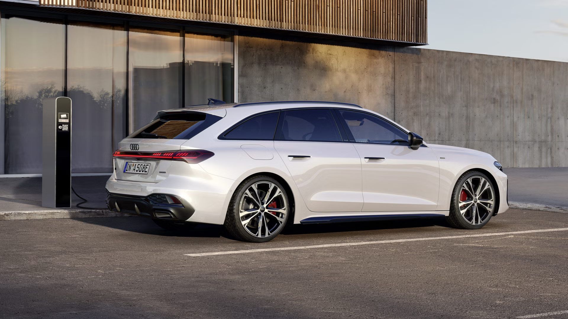 Biely Audi A5 Avant e-hybrid zaparkovaný vedľa nabíjacej stanice