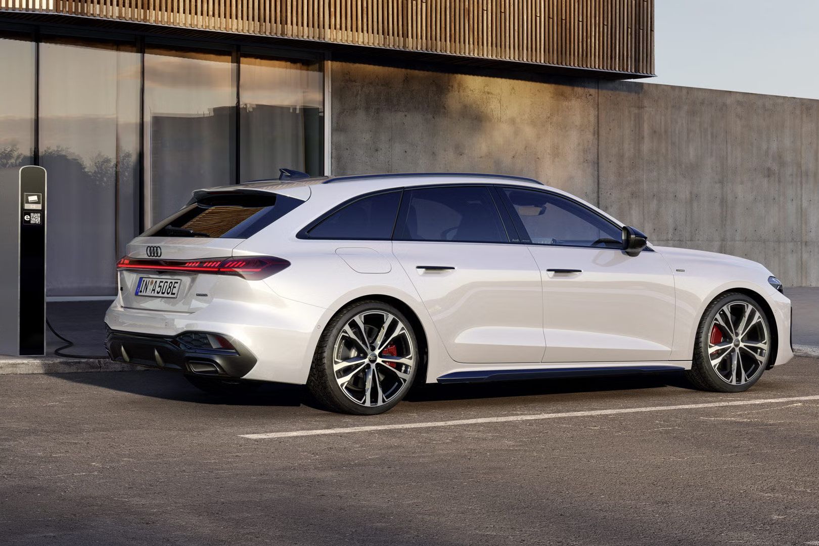 Biely Audi A5 Avant e-hybrid zaparkovaný vedľa nabíjacej stanice