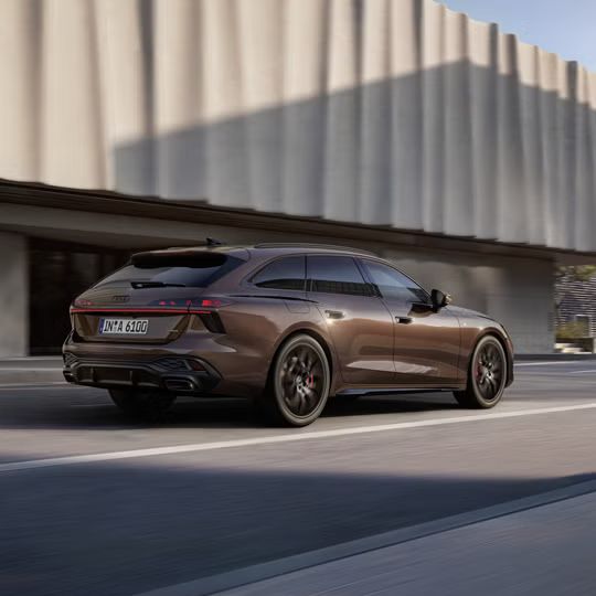 Audi A6 Avant počas dynamickej jazdy na ceste v meste popri modernej budove.