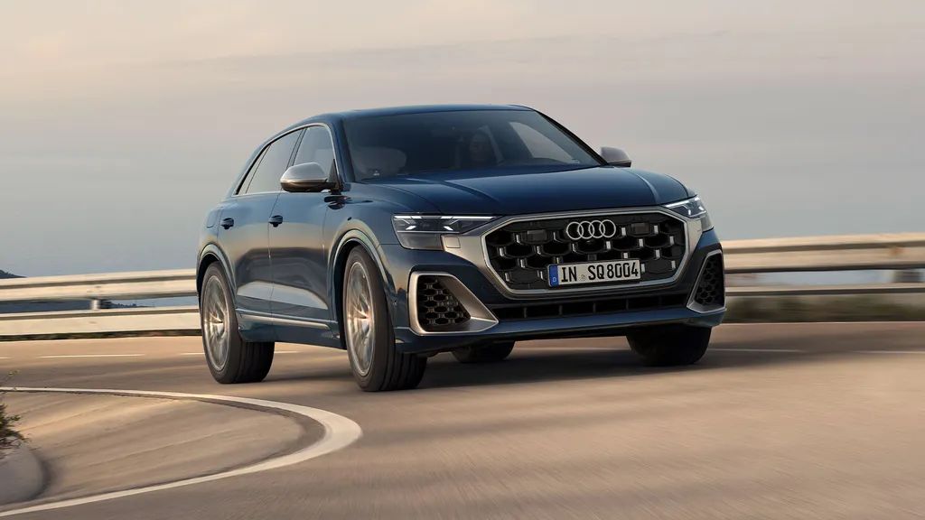 Audi SQ8 SUV jazdí po ceste v zákrute. V pozadí je výhľad na široké more.