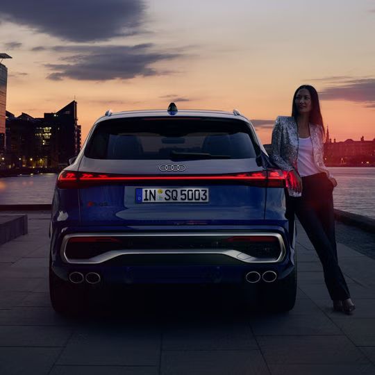 Pohľad na zadnú časť Audi SQ5 SUV, o ktoré sa opiera žena