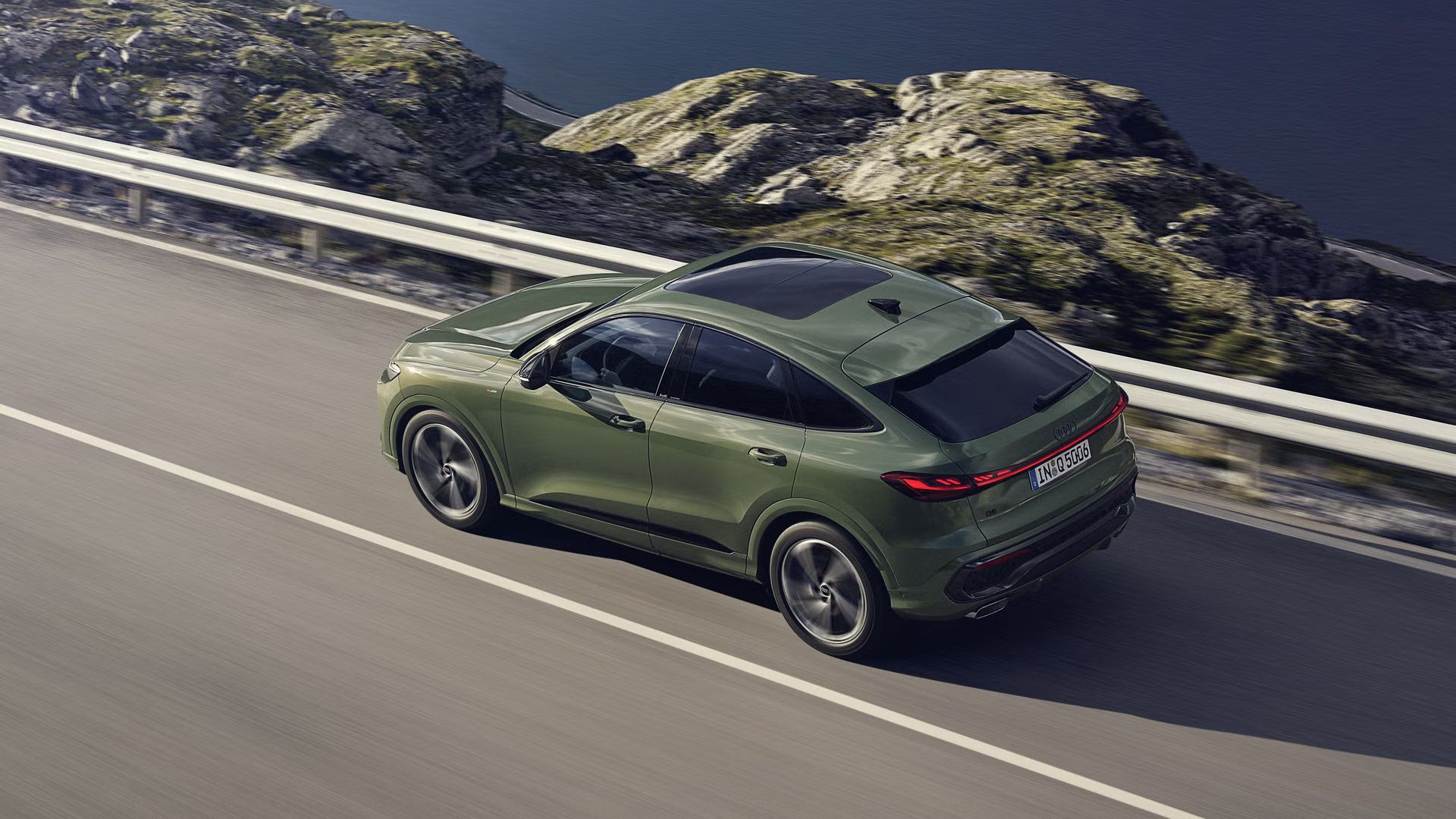 Pohľad na Audi Q5 Sportback zhora počas dynamickej jazdy po ceste popri pobreží.