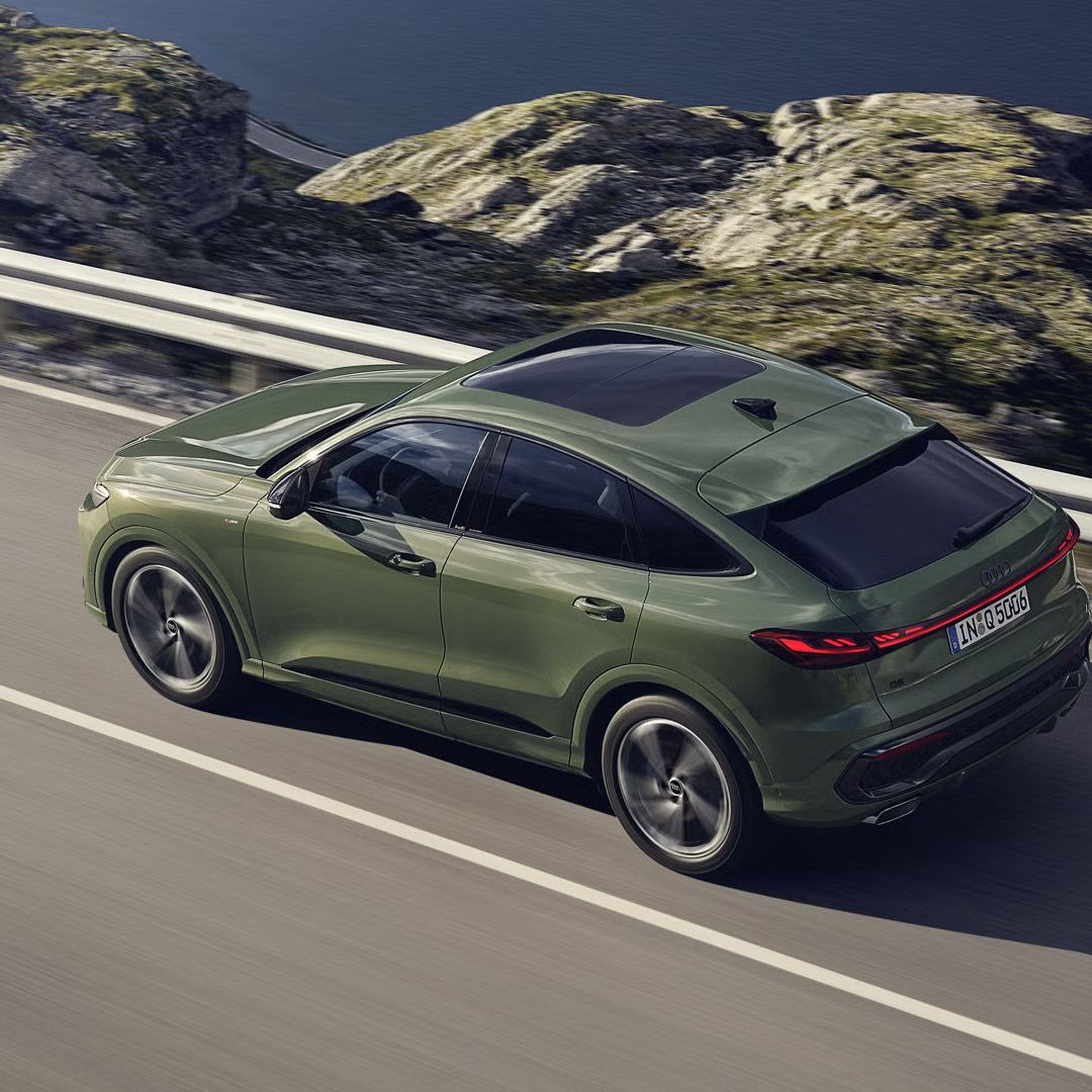 Pohľad na Audi Q5 Sportback zhora počas dynamickej jazdy po ceste popri pobreží.